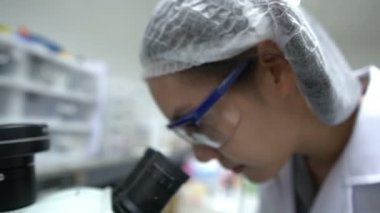 Laboratuvarda çalışan Asyalı bilim adamı deneylerin sonuçlarını araştırıyor.