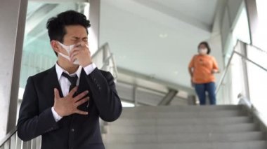 İş merkezinde öksürürken maske takan Asyalı adam, koronvirüs konsepti