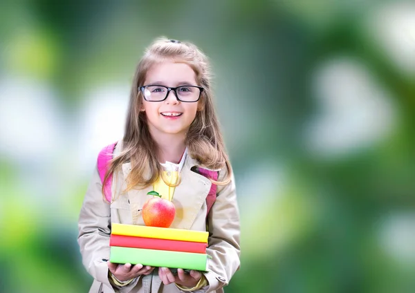 Usmívající se dítě dívka s knihy batoh apple. Zpátky do školy. — Stock fotografie