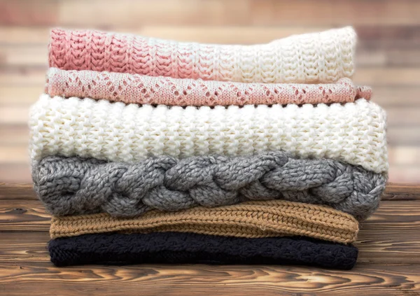 Winter knitted clothes stack on wooden background. — Stock Photo, Image