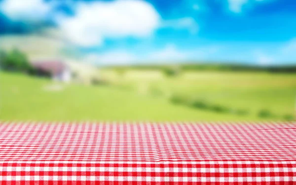 Red checkered tablecloth top view green nature blurred backgroun