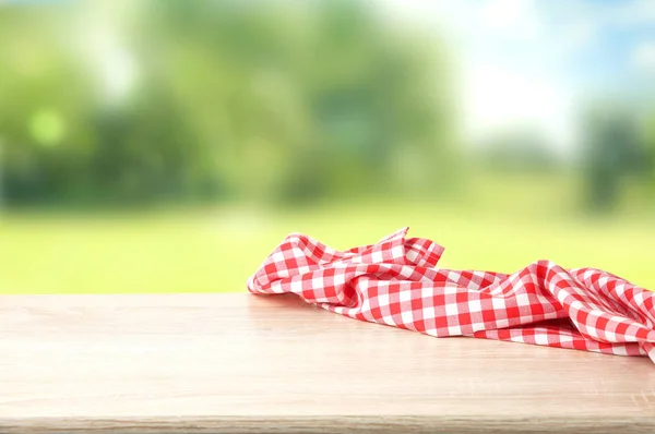 Red checkered picnic cloth on wooden table empty space backgroun