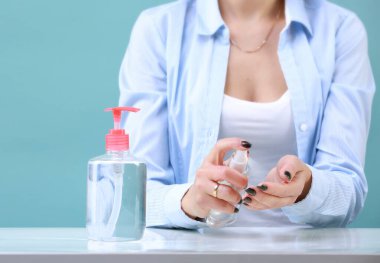 Kadın el antibakteriyel sprey kullanıyor. Kız ellerini antibakteriyel dezenfektan, dezenfektan şişesi ile siliyor. Coronavirus koruması..
