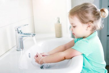 Çocuk ellerini sabunla yıkıyor, beyaz çocuk banyoda. Hijyen kavramı..