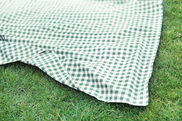 緑の芝生の背景に青いピクニック布チェックテーブルクロストップビュー 空のスペースフード広告デザインの背景 — ストック写真