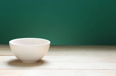 Tahta boş uzay masası ve yeşil arka planda bir kase. Yemek arkaplanı. Boş tabak..