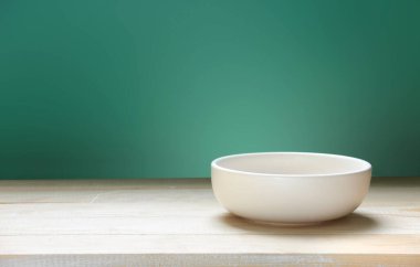 Tahta boş uzay masası ve yeşil arka planda bir kase. Yemek arkaplanı. Boş tabak..