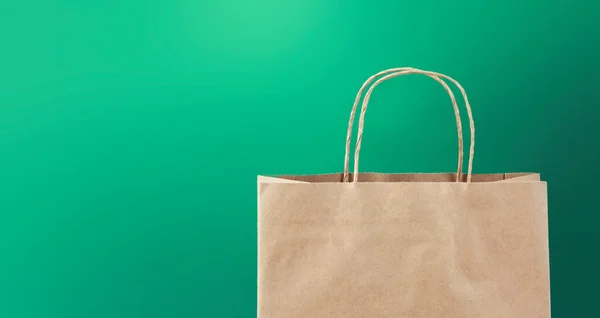 緑の背景の空きスペースにクラフト紙のショッピングバッグ — ストック写真