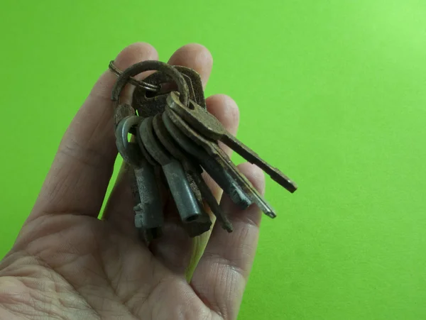 녹색 배경 위에 손에 들고 있는 오래 된 녹슨 열쇠 — 스톡 사진