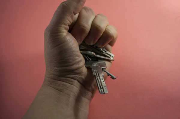 Hand mit angewinkelten Fingern in der Faust mit Schlüsseln auf rosa Hintergrund — Stockfoto