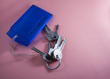 Pembe arka planda bir bavul ve iki örgü anahtarı var.