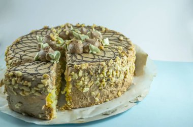 yuvarlak lezzetli krema ve krema çiçekleriyle süslenmiş fındıklı pasta beyaz ve mavi arka planda