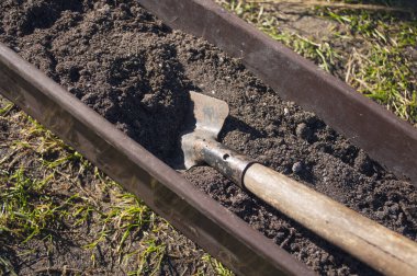 Açık havada plastik bir kutu, karanlık toprakla dolu, ilkbaharda çiçek ve sebze tohumları ekmeye hazırlanıyor..