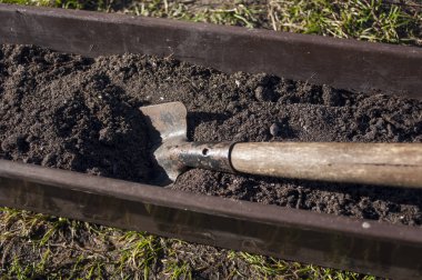 Açık havada plastik bir kutu, karanlık toprakla dolu, ilkbaharda çiçek ve sebze tohumları ekmeye hazırlanıyor..