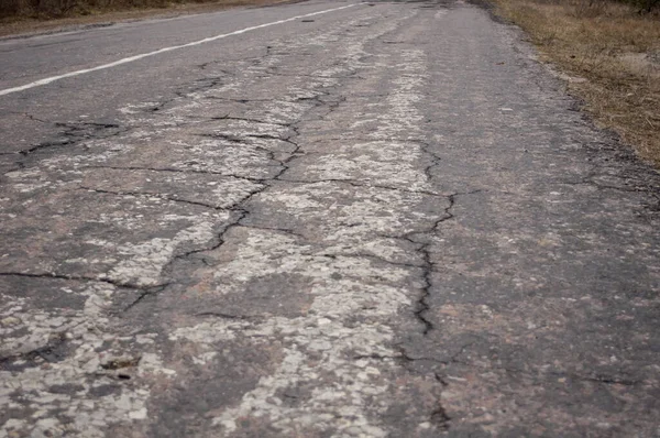 Kötü bir yolun fotoğrafı, yok edilmiş gri asfalt, yakın plan.