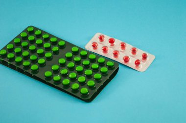 Kırmızı ve yeşil haplar, vitaminler, tablet, mavi arka planda ilaç.