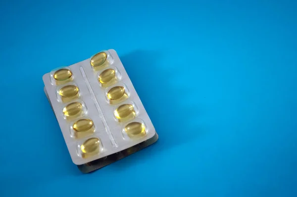 Blister of yellow pills, vitamins, tablet, medicine  on blue background