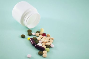 Hapları ve şişeyi mavi arka planda haplar için karıştır. Mavi arka plana beyaz kavanozlar serpiştirilmiş haplar. Metin için alanı kopyala