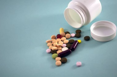 Hapları ve şişeyi mavi arka planda haplar için karıştır. Mavi arka plana beyaz kavanozlar serpiştirilmiş haplar. Metin için alanı kopyala