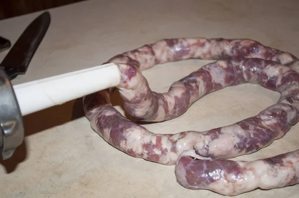 Evde ev yapımı sosis yapıyorum. Domuz bağırsağını etle doldurmak. Fotoğraf, bağırsağın ve zaten doldurulmuş sosisin bir kısmının bulunduğu bir tüp gösteriyor. Sosise odaklan.