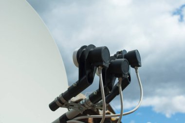 Bulutlu arka planda üç dönüştürücüsü olan parabolik dengeli bir anten. Kablolu üç siyah dönüştürücü ve antenin bir kısmı kapalı.