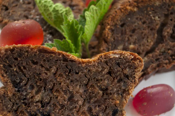 Pieces of chocolate cake and red jelly candies on a white plate decorated with mint close up