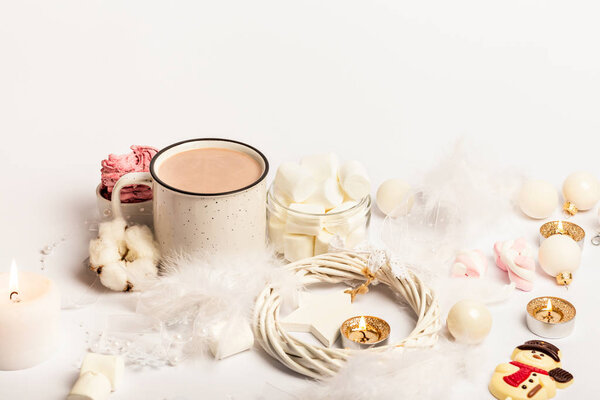 Чашка горячего ароматного какао со сладкими зефировыми свечами на белом фоне. Зимнее рождественское настроение. Белые елочные украшения. Снеговик
.