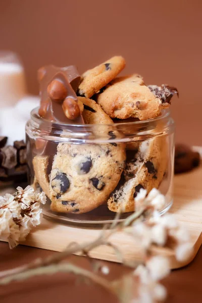 Shortbread cookies with dark chocolate and pieces of milk chocolate with nuts. Beautiful rustic food composition with cookies. Shortbread cookies and milk chocolate on a brown background.