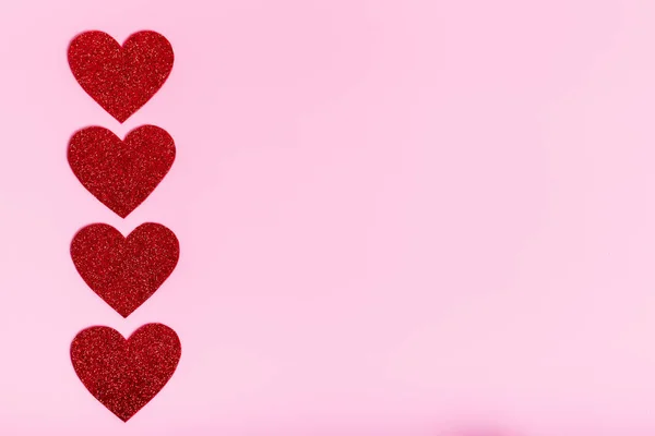 Valentine`s day poster with red hearts on a pink background.