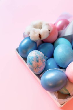 Paskalya süslü yumurtalarla pembe arka planda bir kutuda güzel sakin bir hayat..