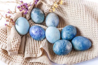 Renkli paskalya yumurtaları ve beyaz arka planda kırsal tarzda bahar çiçekleri olan güzel sakin bir hayat..