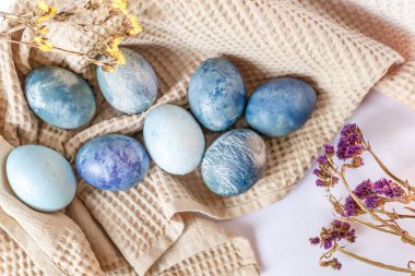 Renkli paskalya yumurtaları ve beyaz arka planda kırsal tarzda bahar çiçekleri olan güzel sakin bir hayat..