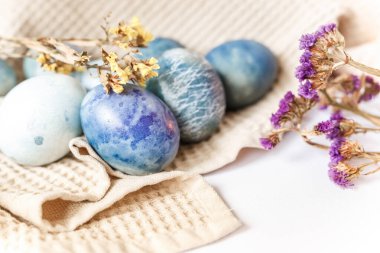 Renkli paskalya yumurtaları ve beyaz arka planda kırsal tarzda bahar çiçekleri olan güzel sakin bir hayat..