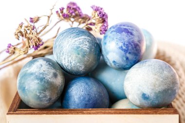 Ahşap bir kutuda boyanmış paskalya yumurtaları ve beyaz arka planda bahar çiçekleri.. 