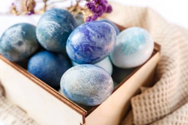 Ahşap bir kutuda boyanmış paskalya yumurtaları ve beyaz arka planda bahar çiçekleri.. 