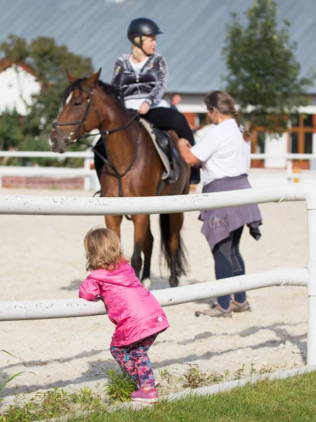 Menina assistindo cavalo cavaleiro — Fotografia de Stock