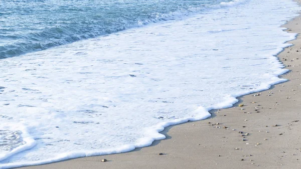 Пена на песке вдоль моря — стоковое фото