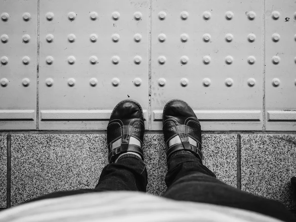 Ноги на залізничній платформі в чорно-білому, концепція мандрівника — стокове фото