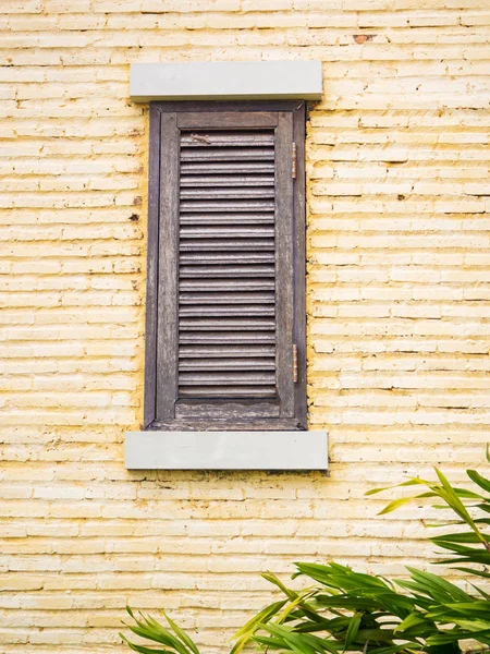 Vintage dřevěné okno na žluté cihlové zdi — Stock fotografie