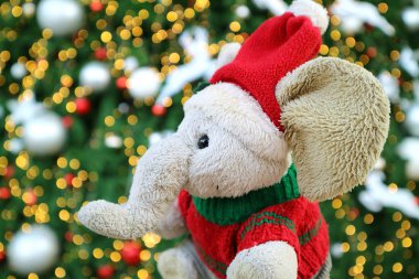Noel Baba şapkalı sevimli Fil bebek Parıldayan Noel ağacının önünde