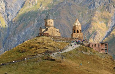 Gürcistan 'ın başkenti Kazbegi' deki Stepantsminda kasabasındaki ünlü Gergeti Trinity Kilisesi 'ni ziyaret eden geniş bir grup insan.