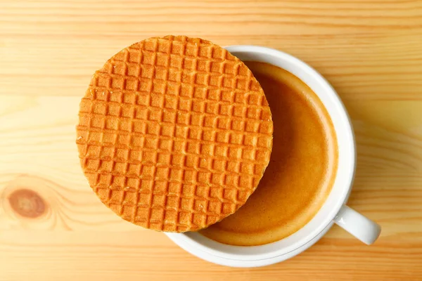 Tahta Masa 'da servis edilen sıcak kahve fincanının üstüne konmuş Stroopwafel' in en iyi görüntüsü.