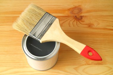 Açılmış bir boya kutusundaki boya fırçası ahşap arka planda izole edilmiş.