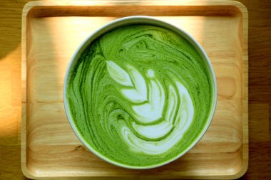 Top View of a Cup of Hot Matcha Green Tea Latte on Natural Wooden Tray