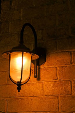 Vertical image of retro style lamp on the old brick wall
