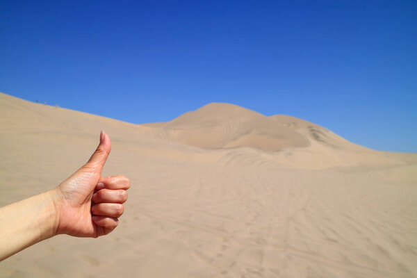 Woman's Hand Thumbing Up to the Amazing View of Huacachina desert in Ica region of Peru, South America