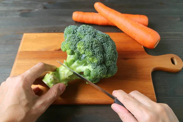 Man Hand Cutting Brokoli Wooden Cutting Board Blurry Carrots Background — Stok Foto