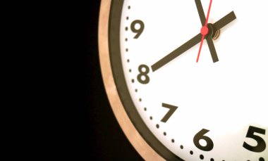 Duvarda asılı kalan saatin bir kısmı saat 8 yönünde, siyah arkaplanda.