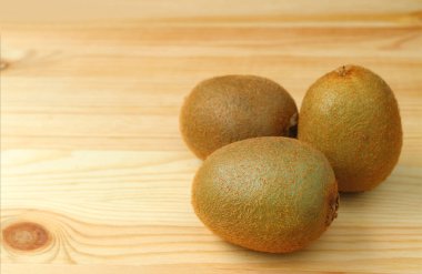 Tahta masada üç taze kivi meyvesi. Metin ve tasarım için boş yeri var.