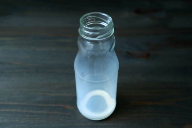 İçtikten sonra boş süt şişesi koyu renkli ahşap masada izole edilmiş.